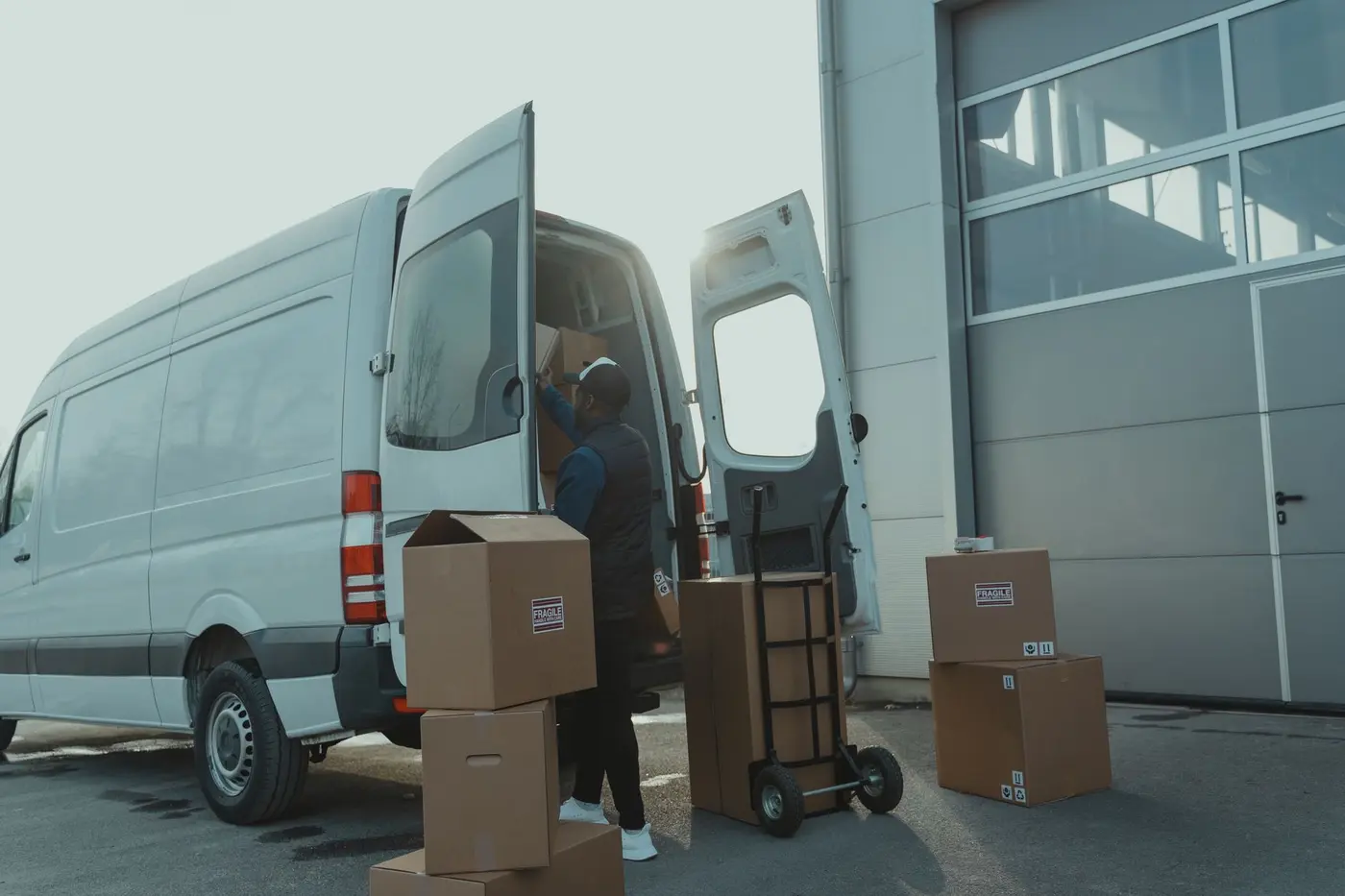 A driver lifting cardboard boxes out of the back of a cargo van