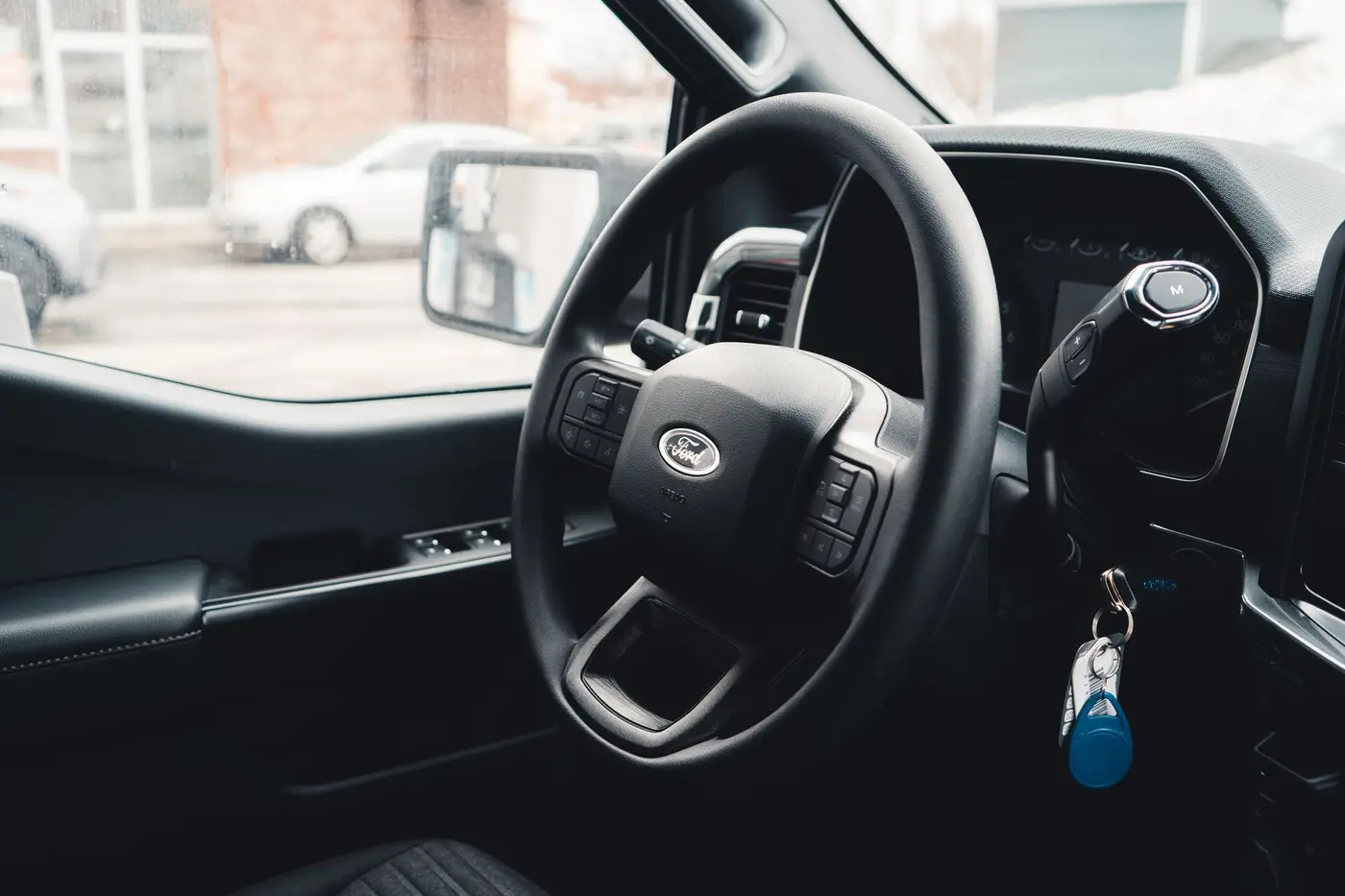The interior of a vehicle at handover, keys still in the ignition and the lot visible through the window